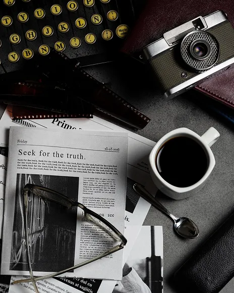 Newspapers, camera and coffee on a desk, representing editorial negotiation with publishers