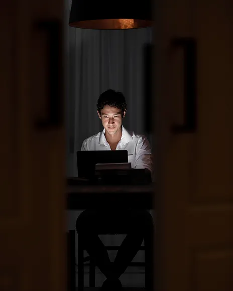 Person working alone in a dark room, representing anonymous blog attacks