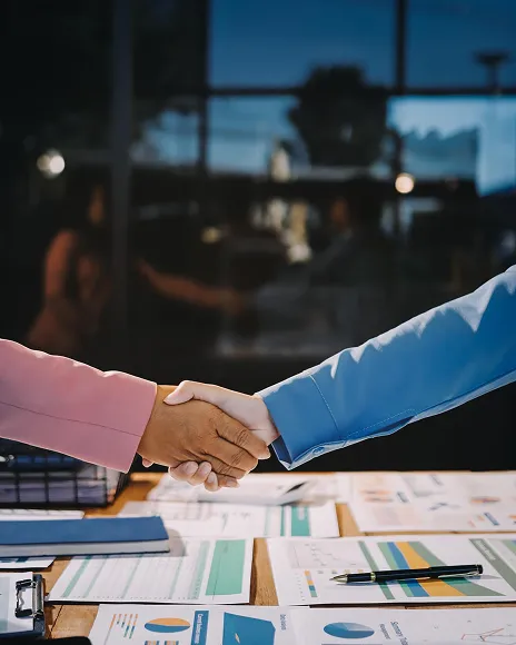 Business handshake over charts, representing brand trust