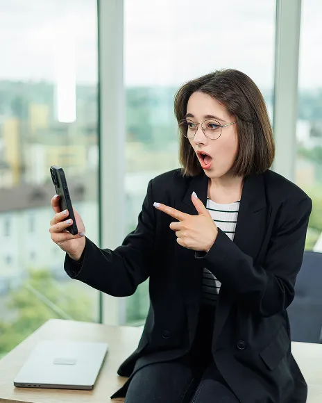 Woman pointing at a phone in shock, representing an executive impersonated on Instagram
