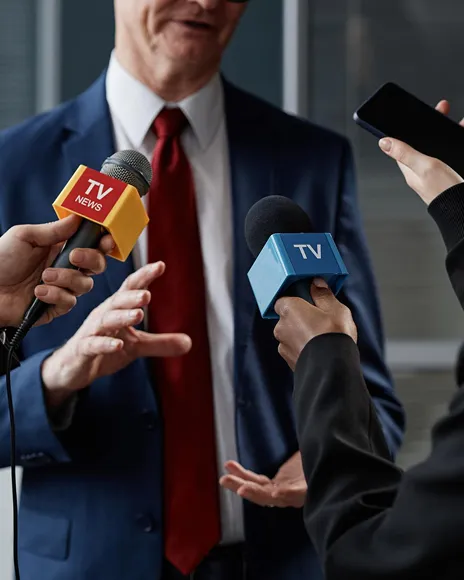 Executive speaking to TV reporters holding microphones, representing founder visibility